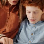 A mother and son bonding as they use a tablet together indoors.