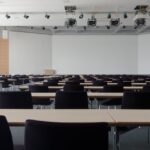 Spacious contemporary conference room with rows of tables and chairs, ready for meetings.