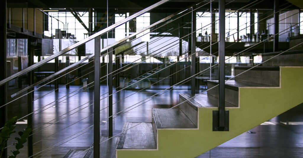 Spacious interior featuring modern staircase with glass railings and metal design elements.