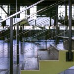 Spacious interior featuring modern staircase with glass railings and metal design elements.