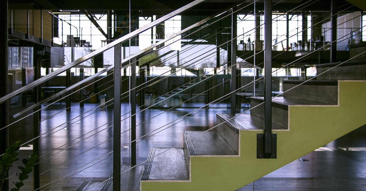 Spacious interior featuring modern staircase with glass railings and metal design elements.