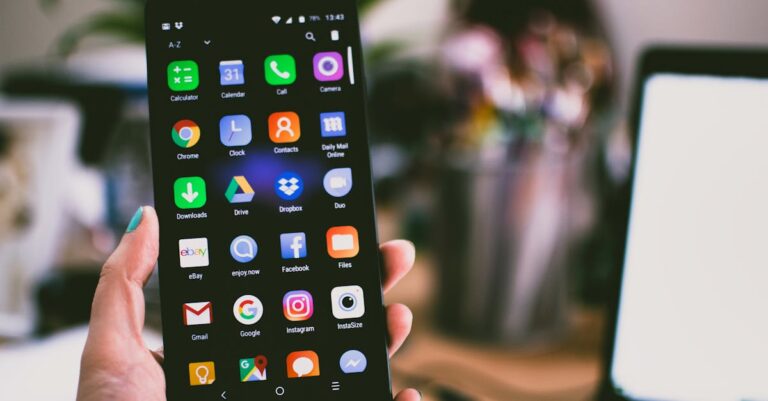 A close-up image of a person's hand holding a smartphone displaying various popular apps.