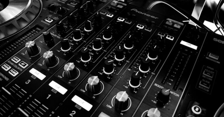 Black and white close-up of a DJ's audio mixing console with knobs and controls.