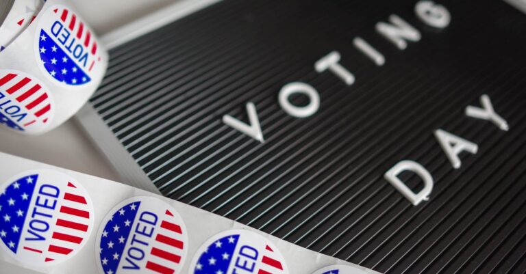 I Voted stickers with an American flag design and Voting Day sign symbolize U.S. electoral participation.