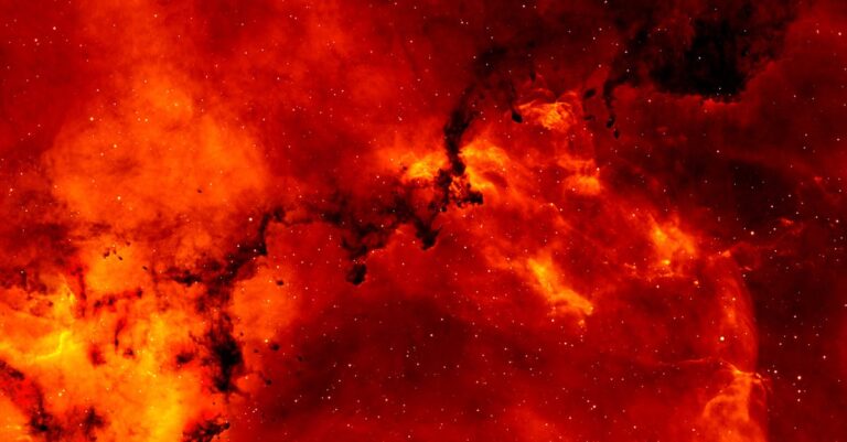 A stunning view of a red cosmic nebula, glowing intensely against a backdrop of stars.