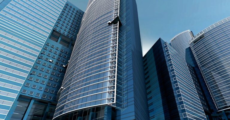 Futuristic urban skyscrapers with glass facades reflecting a vibrant blue sky.