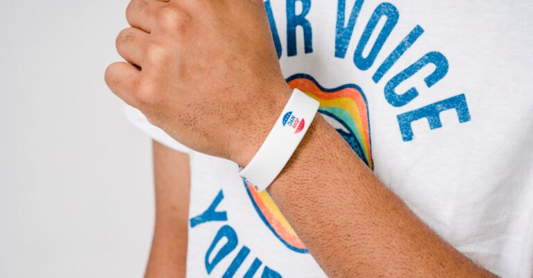 Person wearing a white 'I Voted' wristband and a shirt with 'Your Voice' text.