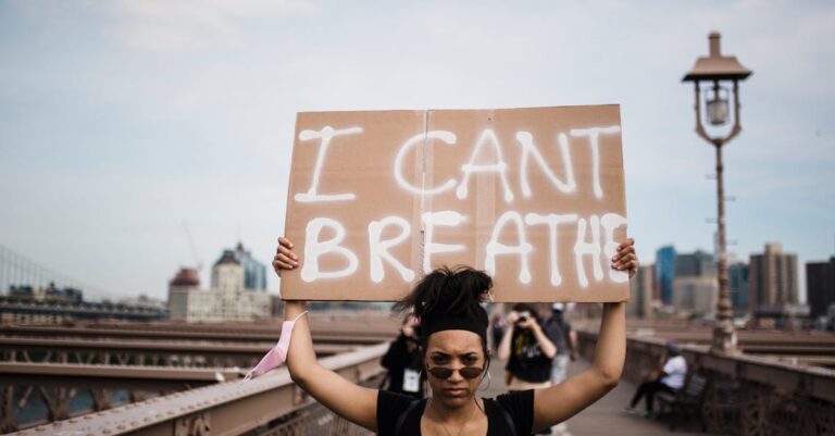 A protester holds an 'I Can't Breathe' sign during a demonstration on a bridge.