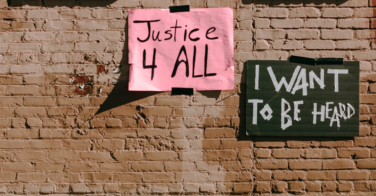 Street activism signs on a brick wall promoting social justice and freedom of speech.