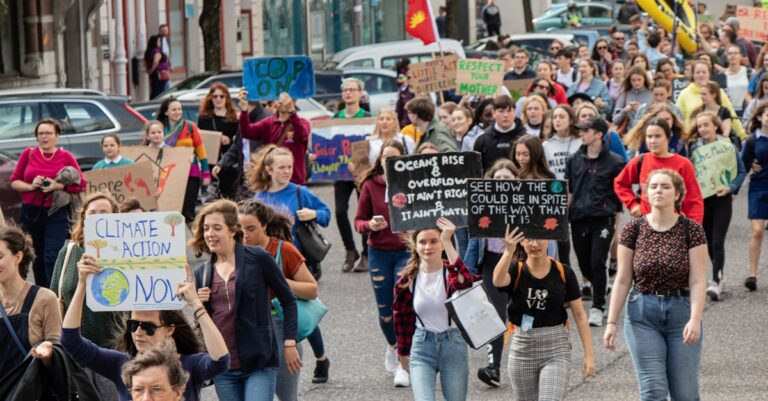 A vibrant climate march with diverse group holding signs demanding climate action.