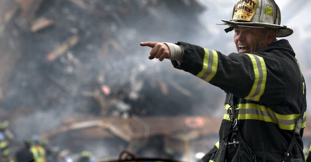 A firefighter in action at a disaster scene, directing rescue operations amidst smoke and debris.