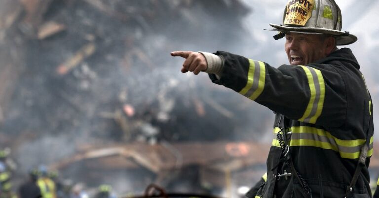 A firefighter in action at a disaster scene, directing rescue operations amidst smoke and debris.
