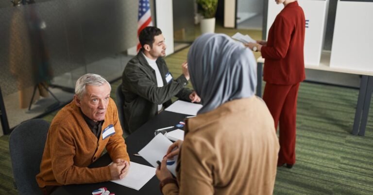 Adults engaging in the voting process at an indoor polling station, representing diverse backgrounds and social responsibility.