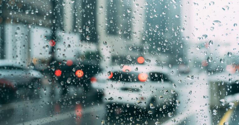 Blurred city traffic seen through a window with raindrops, a perfect rainy day scene.