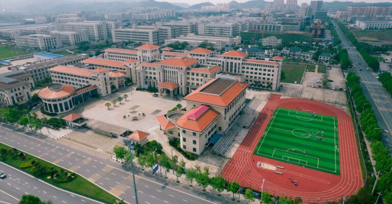 Aerial view of a modern school campus with sports field in Jiujiang, China.