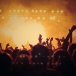 Energetic music concert with a vibrant crowd cheering under bright stage lights.