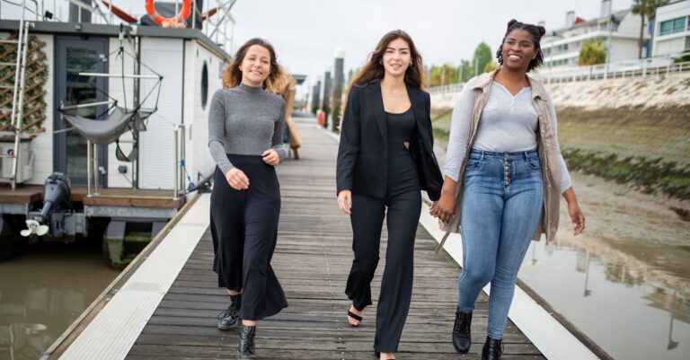 Three young women happily walking on a pier in Portugal, enjoying a moment of friendship and joy.