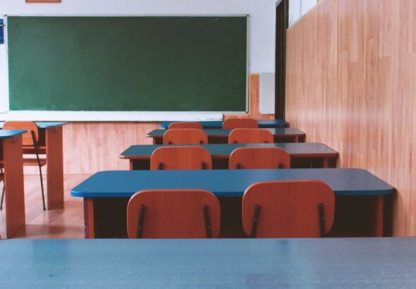 A tranquil empty classroom with wooden furniture and a green chalkboard, perfect for educational themes.