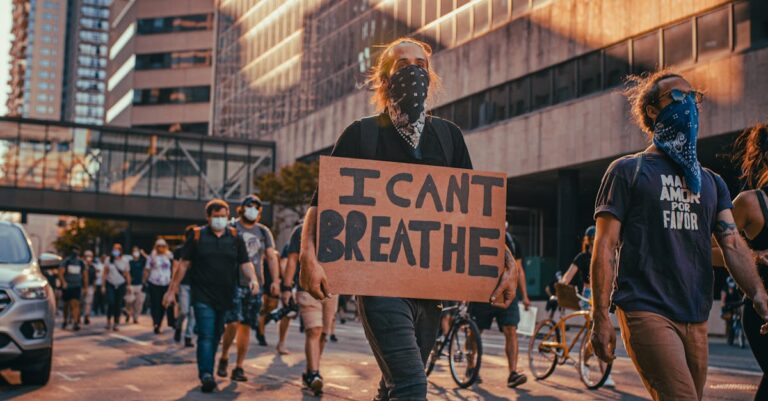People protesting against racial injustice in Minneapolis, holding signs like 'I Can't Breathe'.