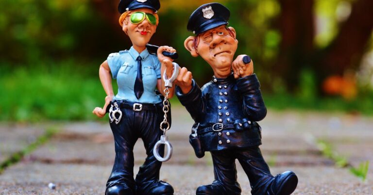 Two playful police figurines, complete with handcuffs and batons, depicted in a comical outdoor setting.
