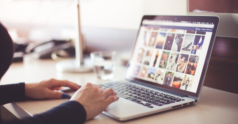 Close-up of hands typing on a laptop with an image gallery open on the screen.