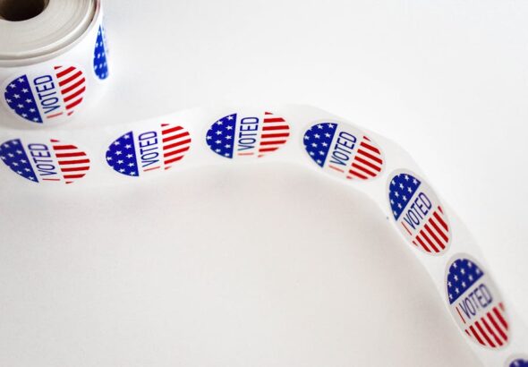 Close-up of a roll of 'I Voted' stickers featuring the American flag design on a white background.