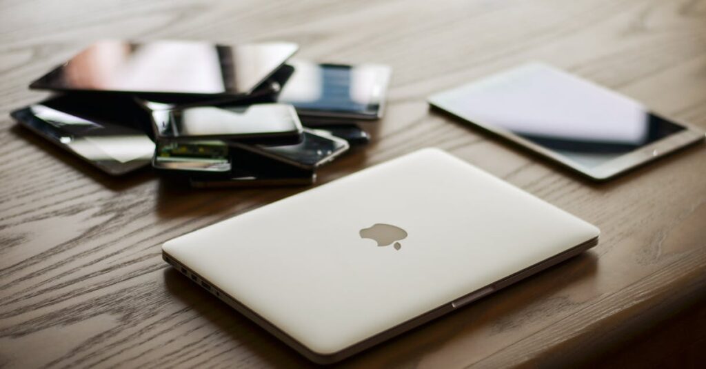 A variety of modern electronic gadgets, including a laptop and smartphones, on a wooden table.