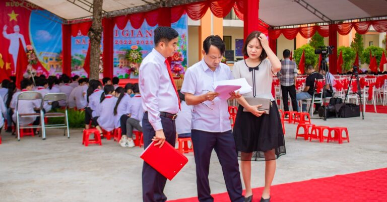 A formal outdoor ceremony with people in formal attire under decorative tents and banners.