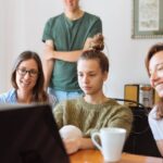 A diverse group of adults at work, enjoying a casual meeting indoors with focus and smiles.
