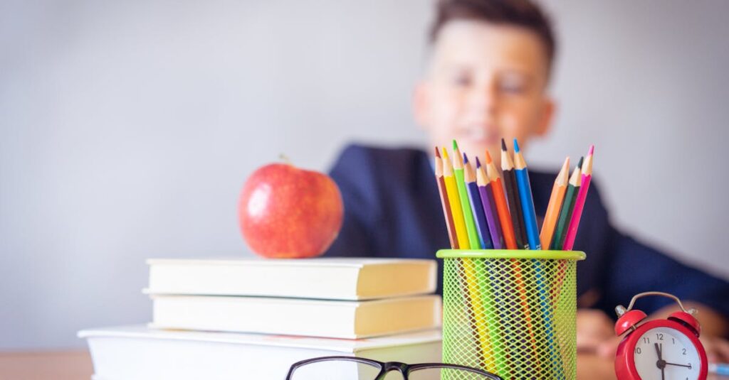 Schoolboy smiling behind a desk with books, pencils, and an alarm clock symbolizing study and creativity.