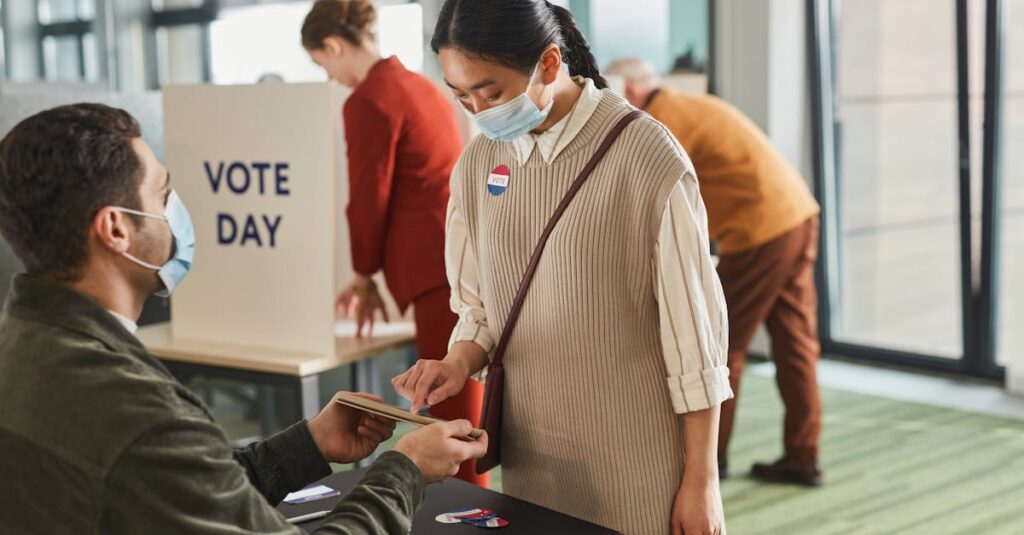 Voters casting ballots indoors on Election Day, wearing masks and using tablets for contactless voting.