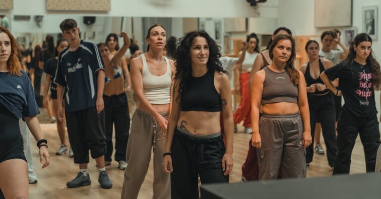 A diverse group of adults participating in a dance class in a modern, indoor studio setting.