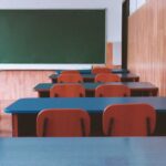A tranquil empty classroom with wooden furniture and a green chalkboard, perfect for educational themes.