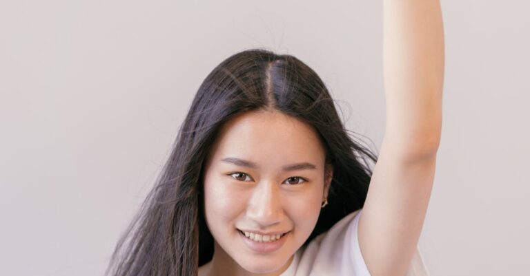 Cheerful young woman in white shirt with raised fist showing a vote sticker.