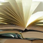 A close-up of a stack of open books with pages fanned out, capturing a study atmosphere.