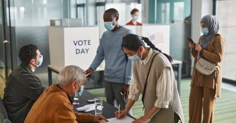 A diverse group of adults casting votes indoors on election day, maintaining safety protocols.