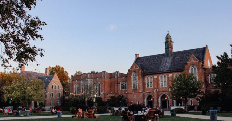 Scenic view of Notre Dame campus with Gothic-style buildings and students on a green field.