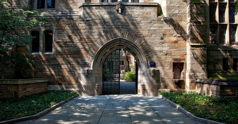 Gothic-style stone archway entrance at Yale University campus, surrounded by greenery.