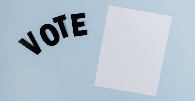 Flat lay of blank paper with 'VOTE' letters on light blue background, ideal for election-themed content.