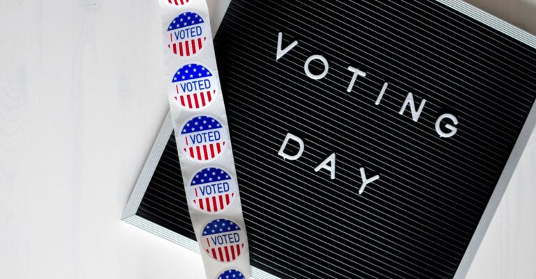 Close-up of a Voting Day sign and roll of I Voted stickers.