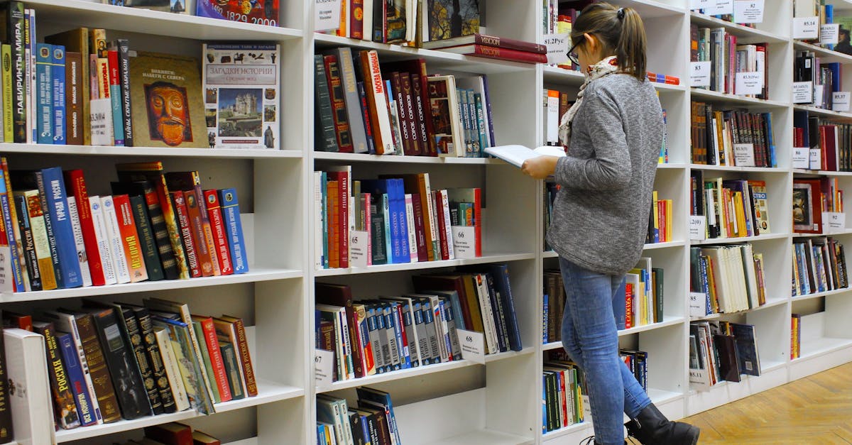 A young woman stands reading a book in a well-stocked library.