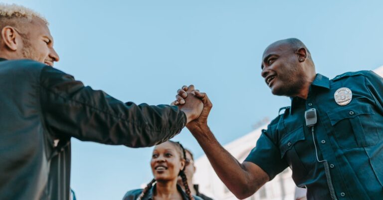 A friendly handshake between a police officer and a civilian during an outdoor community event.