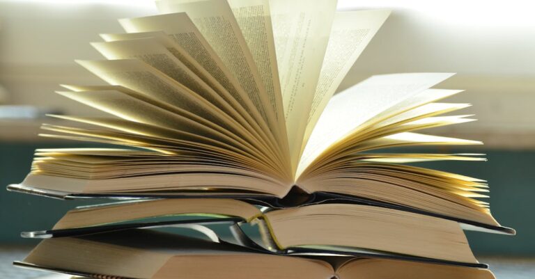 A close-up of a stack of open books with pages fanned out, capturing a study atmosphere.