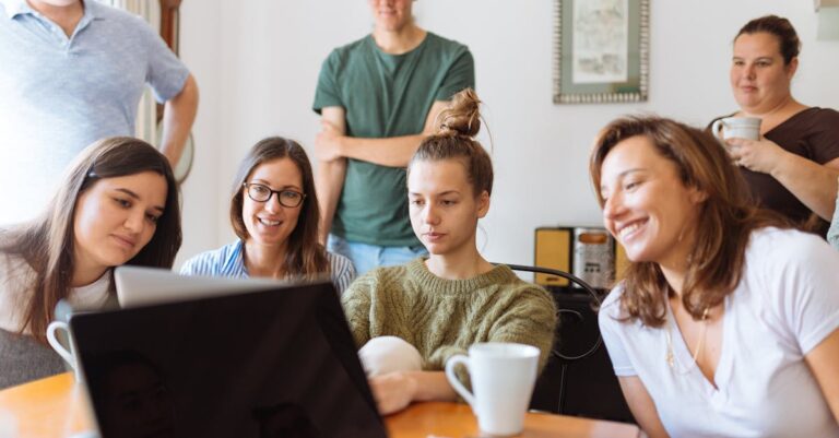 A diverse group of adults at work, enjoying a casual meeting indoors with focus and smiles.