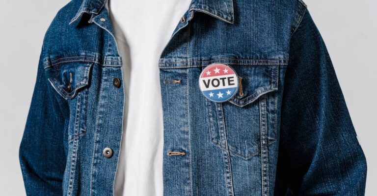 Close-up of a denim jacket with a patriotic vote badge promoting political engagement.