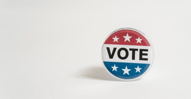 Close-up of a red, white, and blue vote button with stars on a white background.