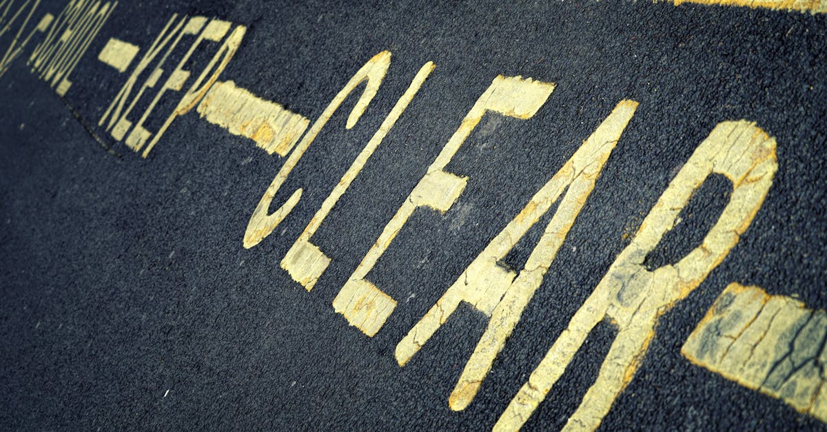 Close-up of yellow road markings with 'KEEP CLEAR' instruction on asphalt surface.