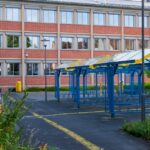 A contemporary school building with colorful playground structures on a sunny day.