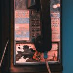Close-up of a vintage pay phone, showcasing unique wear and retro style in an urban environment.