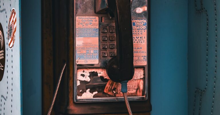 Close-up of a vintage pay phone, showcasing unique wear and retro style in an urban environment.